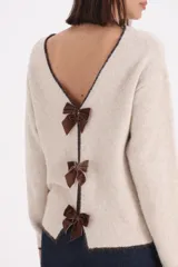 Sweater de tejido de punto en color beige con detalles de terminación en color chocolate en cuello, puños y ruedo. Presenta un diseño de corte holgado con mangas largas y cuello redondo amplio.