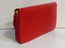 Billetera rectangular con cierre perimetral, confeccionada en cuero con textura de reptil. Cuenta con múltiples compartimentos internos para tarjetas, documentos y billetes, además de un bolsillo interior con cierre para monedas.