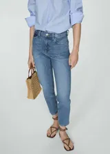 Pantalón jeans de tiro alto estilo mom-fit, color azul con lavado clásico, diseño de cinco bolsillos y cierre frontal con cremallera y botón metálico.