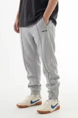 Pantalón de jogging gris melange con costuras frontales marcadas, cintura elástica y cierres en los tobillos. Presenta el logo de la marca bordado en la pierna izquierda.