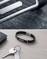 Pulsera masculina con banda de goma negra con textura de fibra de carbono y placa central de acero inoxidable.