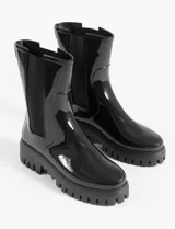 Botas de lluvia de caña media con acabado brillante, diseño tipo chelsea con paneles laterales elásticos en color negro y suela track dentada de plataforma.