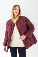 Chaqueta acolchada de color negro con diseño de costuras onduladas. Presenta cuello redondo, cierre frontal con botones a presión y dos bolsillos frontales tipo cargo con solapa y detalle de hebilla. Posee un corte holgado y mangas largas.