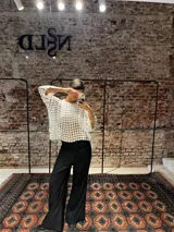 Blusa blanca de encaje con diseño de flores pequeñas entrelazadas, de corte holgado y mangas tres cuartos.