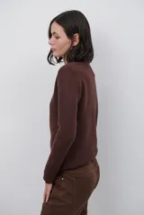 Polera de tejido de punto fino en color beige, con cuello alto y mangas largas con puños acanalados.