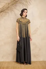 Capa negra con cuello alto y bordados dorados. Presenta flecos largos dorados que caen desde los hombros.
