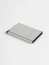Tarjetero rígido de aluminio en color gris plateado con mecanismo de extracción inferior, diseñado con bloqueo RFID.