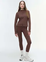 Campera deportiva de cuello alto con cierre frontal de doble cursor. Presenta un corte ajustado que realza la silueta, bolsillos laterales con cierre y mangas largas con puños con abertura para el pulgar.