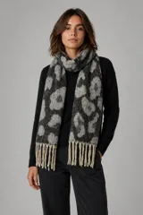 Bufanda de tejido suave con estampado animal print en tonos negro y gris, terminada con flecos en color crudo en los extremos.
