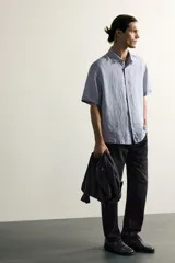 Jeans regular fit de mezclilla negra con efecto lavado, corte recto y tiro medio. Cuenta con diseño de cinco bolsillos y cierre frontal con cremallera y botón.
