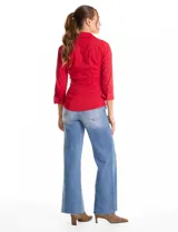 Camisa entallada de color rojo, con cuello solapa, escote en V y cierre frontal con botones. Presenta una pechera con alforzas horizontales y mangas tres cuartos con puños anchos rebatibles.