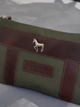 Sobre tipo cartuchera de lona naranja con detalles y apliques en cuero marrón. Presenta un aplique metálico en forma de caballo y un parche con el logo de la marca grabado en el frente.