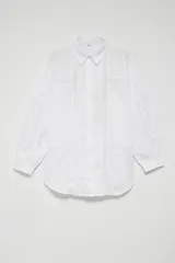 Camisa blanca de manga larga con detalles de encaje vertical y horizontal. Presenta cuello clásico, cierre frontal con botones ocultos y puños abotonados.