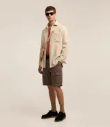 Bermuda cargo masculina de sarga lavada en color marrón, con bolsillos laterales con solapa, trabillas para cinto y cierre frontal con botón y cremallera.
