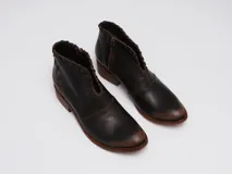 Botinetas de cuero color marrón con efecto desgastado en la puntera y el talón. Presentan un diseño con corte en V en el empeine con detalles de costuras decorativas, cierre lateral y taco bajo de madera.