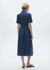Vestido midi de estilo camisero en tejido satinado fluido, color azul. Presenta cuello camisero, cierre frontal con botones, mangas cortas con dobladillo y dos bolsillos de parche en el pecho. Incluye un lazo ajustable en la cintura para entallar la silueta.
