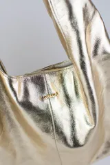 Cartera de cuero vacuno con pelo en diseño animal print similar a piel de ciervo, silueta triangular y asa integrada.