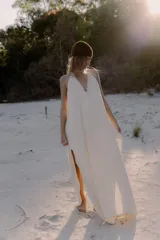 Vestido largo de color blanco, con escote en V pronunciado y tiras largas que permiten anudarlo de múltiples formas. Presenta tajo en ambos laterales y forro interno.