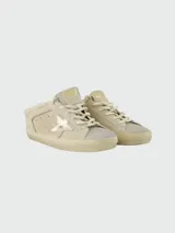 Zapatillas Golden Goose modelo Super Star, color beige con acabado en gamuza. Presentan el diseño icónico de la marca con estrella lateral en tono dorado metalizado, suela con efecto desgastado y forro interno de piel sintética.