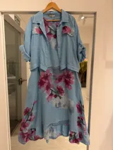 Set compuesto por vestido midi sin mangas y casaca de manga corta con bolsillos frontales, ambos en color celeste con estampado de flores rosas.