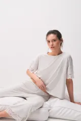 Pijama de modal jersey color gris claro melange, compuesto por una remera de manga corta con detalles de encaje en las terminaciones y un pantalón largo a juego con encaje en el ruedo.