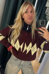 Campera tejida de punto con cierre frontal completo y cuello alto. Presenta un diseño de rombos en la parte superior del frente y franjas horizontales en las mangas, con puños y ruedo acanalados.