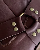 Bota estilo tejana de cuero vacuno color bordó, con detalle de argolla metálica y remaches decorativos.