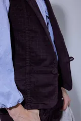 Chaleco de pana color bordó, con cierre frontal de botones y bolsillos laterales.
