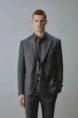 Blazer gris oscuro de corte regular fit con diseño de raya diplomática, confeccionado con mezcla de lana. Presenta solapas de muesca, cierre frontal de dos botones, bolsillos con solapa en la cadera y un bolsillo de vivo en el pecho.
