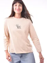 Remera de manga larga color crema con cuello redondo y un estampado central de un ramo de flores rosadas y naranjas en un jarrón azul oscuro.