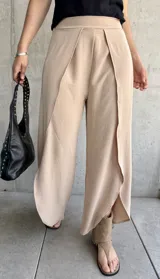Pantalón color beige de corte palazzo con abertura lateral en la parte inferior de la pierna.
