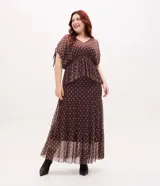 Falda midi en tul de color marrón con estampado geométrico de rombos, cintura elástica y diseño con volados escalonados. Incluye forro corto interior que genera transparencia en la parte inferior.