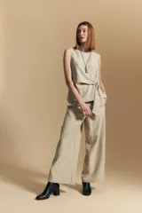 Top sin mangas color beige con finas rayas verticales negras. Presenta un diseño con lazada ajustable en el lateral de la cintura.