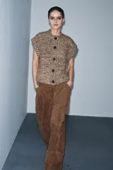 Chaleco de punto grueso con textura jaspeada, cuello redondo, cierre frontal con botones y diseño sin mangas.