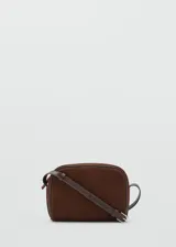 Bolso bandolera de tamaño pequeño confeccionado en piel de serraje color marrón. Cuenta con cierre de cremallera, forro interior de algodón y asa larga ajustable con hebilla metálica.