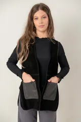 Chaleco de cuero negro con diseño sin mangas, corte recto y bolsillos frontales con contraste de textura. Presenta costuras visibles y un acabado artesanal.