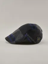 Boina tipo flat cap con diseño de cuadros en tonos gris oscuro y negro, con detalles de líneas en azul. Incluye una etiqueta decorativa lateral de la marca Benson & Thomas.