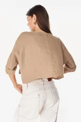 Camisa de lino azul marino, de corte crop y holgado, con cuello redondo, botonadura frontal y mangas amplias con vuelta.