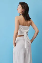 Blusa strapless azul marino de corte asimétrico con terminación en punta y flecos sutiles en el borde inferior, diseño de escote palabra de honor.