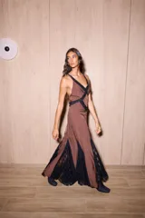 Vestido largo de seda color marrón con estampado de lunares blancos y detalles de encaje negro. Presenta un diseño entallado en el torso, escote en V profundo y espalda descubierta con tiras cruzadas.