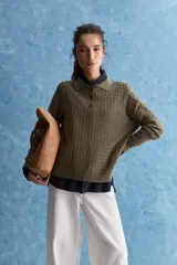 Sweater de punto color verde militar, con cuello polo y cierre frontal de botones, de manga larga con puños elastizados y diseño texturizado con relieve geométrico.