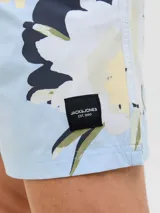 Short de baño de tiro medio con estampado floral en tonos claros sobre fondo celeste. Cuenta con cintura elástica con cordón ajustable, bolsillos laterales y un bolsillo trasero.