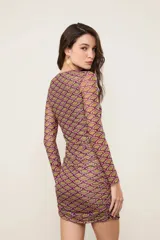Vestido corto ajustado de manga larga y cuello redondo, confeccionado en tejido semitransparente con estampado geométrico multicolor en tonos fucsia, verde y marrón.