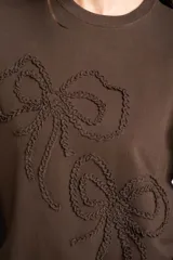 Sweater marrón de algodón con cuello redondo y diseño de moños en relieve bordados en el frente.