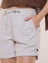 Short de lino de corte recto, color beige, con cintura elastizada y cordón ajustable. Cuenta con bolsillos delanteros aplicados, bolsillos traseros funcionales y ruedo con dobladillo fijo arremangado, detallado en los laterales con presilla y botón a contraste.