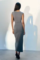 Vestido maxi entallado sin mangas, confeccionado en punto. Modelo con escote asimétrico y detalle de metal en un hombro. Panel drapeado con detalle metálico bajo la cintura para estilizar la silueta.