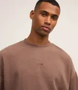 Remera marrón de poliéster y elastano con textura de pana, cuello redondo, manga corta y bordado centralizado de lettering minimalista.