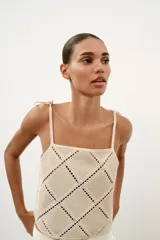 Top de escote recto color beige con tirantes finos ajustables con lazadas. Presenta un diseño con apliques de tejido tipo crochet en patrón geométrico de rombos.
