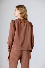Chaqueta marrón a rayas verticales, con cuello redondo, cierre frontal con botones y mangas largas abullonadas con puños abotonados.