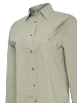 Blusa de manga larga con cuello camisero, color gris claro. Presenta cierre frontal con botones, dos bolsillos frontales con solapa y paneles laterales con ventilación. Confeccionada en tejido con protección UV.